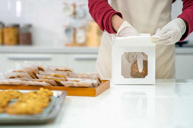 A baker packing subscription cookies in a bag